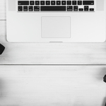 An-overhead-view-of-laptop-with-camera-accessories-on-white-desk